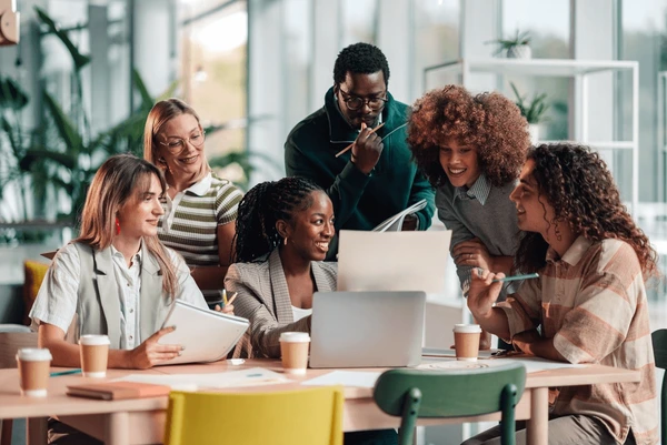 Team members collaborating around a shared desk in a bright office setting